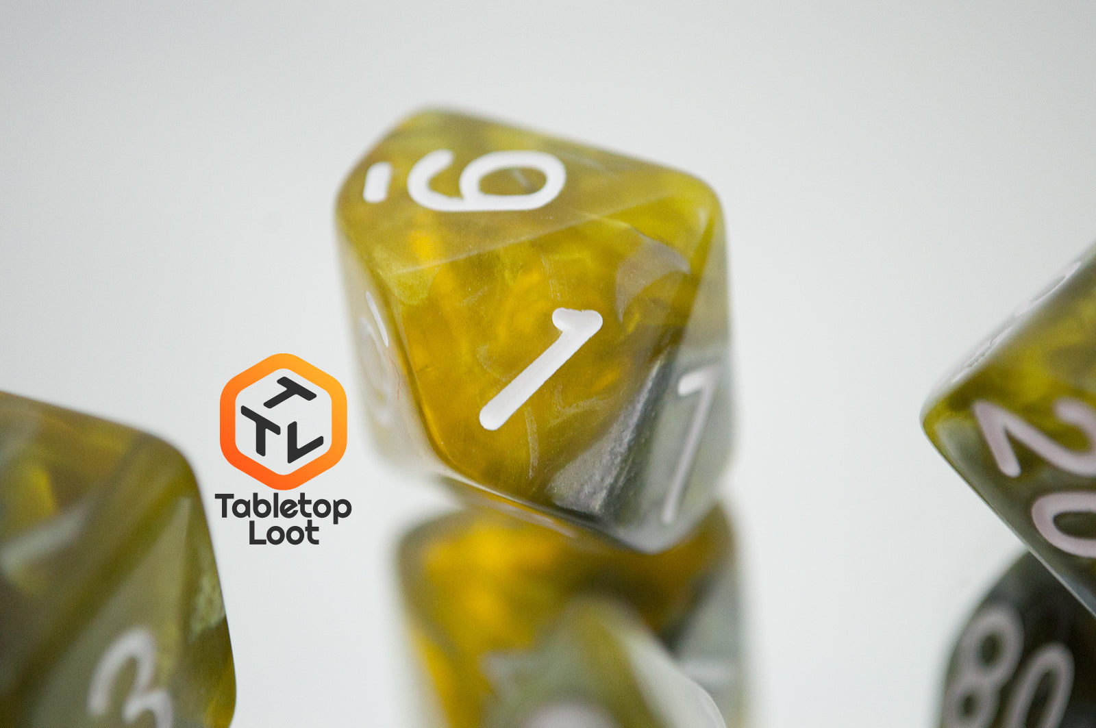 A close up of the D10 from the Disintegrate 7 piece dice set from Tabletop Loot with swirls of silver and gold and white numbering.