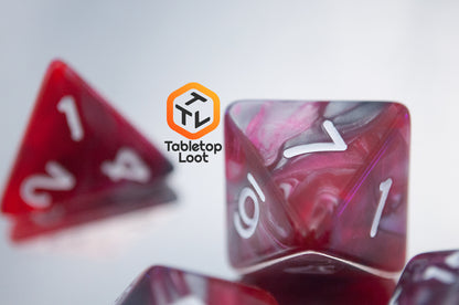 A close up of the Dragon's Blood 7 piece dice set from Tabletop Loot with swirled red and grey resin and white numbering.