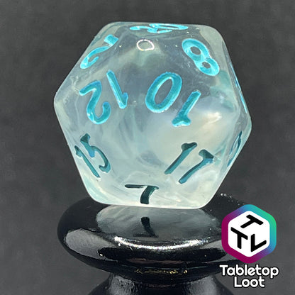 A close up of the D20 from the Frostmaiden 7 piece dice set from Tabletop Loot with swirls of frosty white in clear resin and blue numbering.