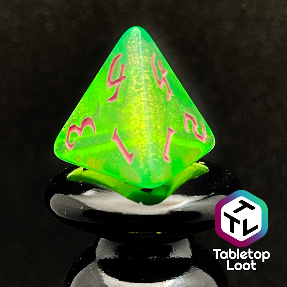A close up of the D4 from the Sour Apple 7 piece dice set from Tabletop Loot; shimmery green dice with pink gothic numbering.