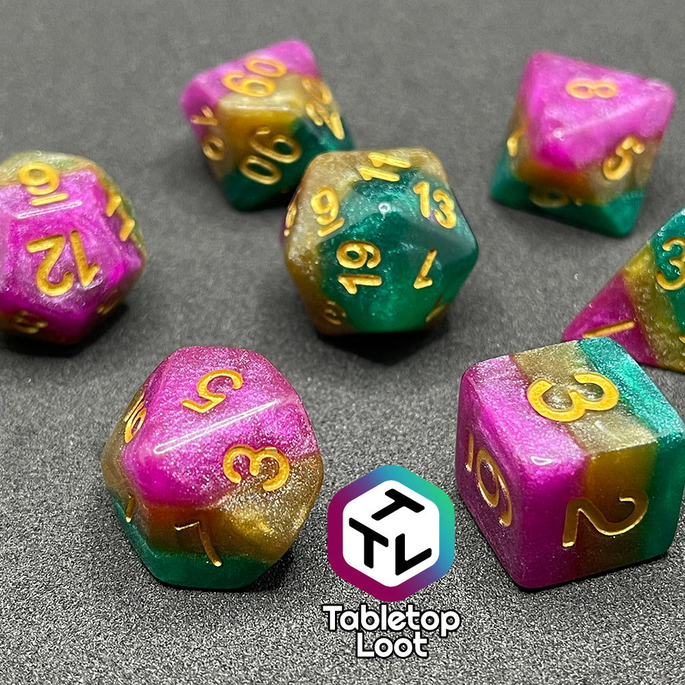A close up of the Gem of Brightness 7 piece dice set from Tabletop Loot with stripes of glittery pink, gold, and green and inked in gold.