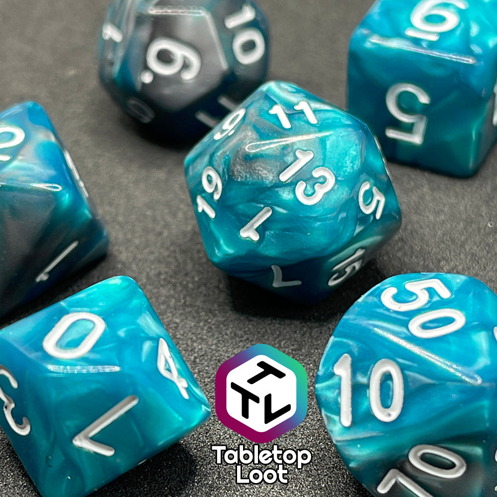 A close up of the Hunter's Mark 7 piece dice set from Tabletop Loot with pearlescent swirls of blue and silver and white numbering.