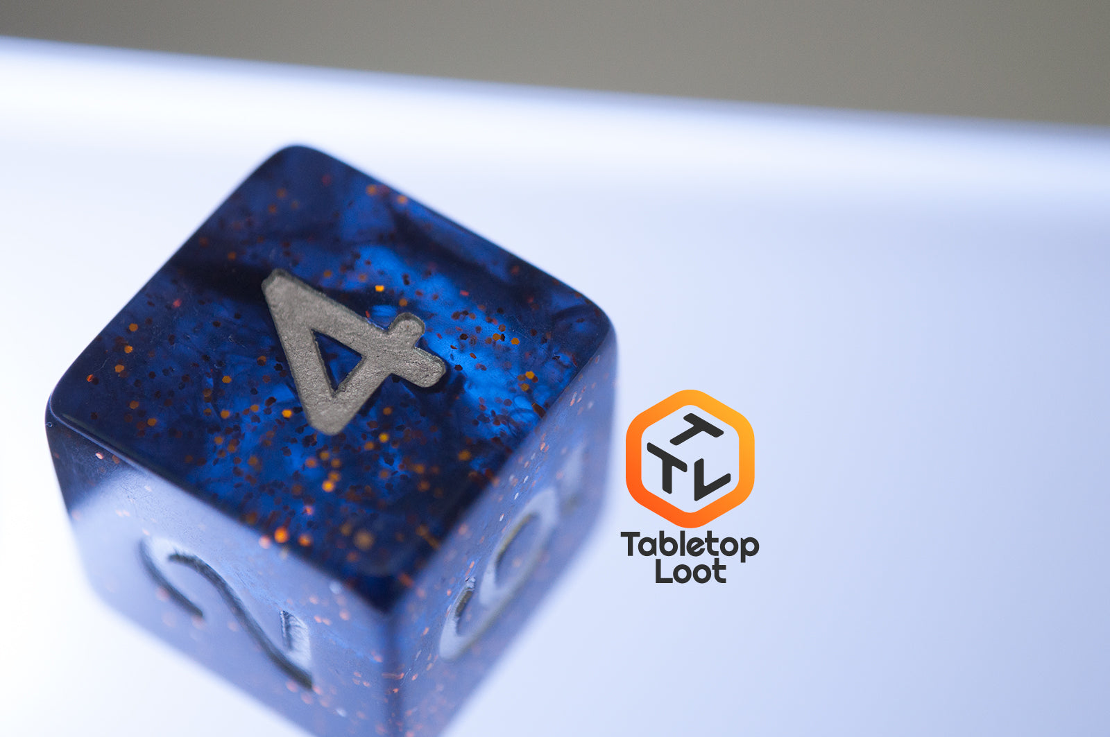 The Midnight Sky 7 piece dice set from Tabletop Loot with dark navy blue resin, gold glitter, and silver numbering.