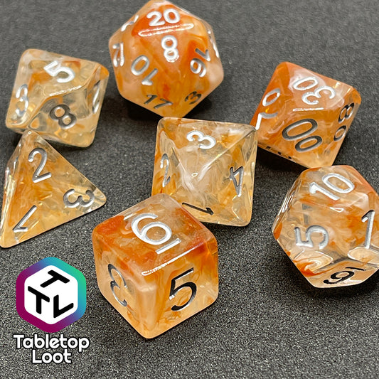 The Hunter's Moon 7 piece dice set from Tabletop Loot with swirls of orange and white in clear resin and white numbering.