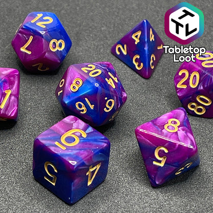 A close up of the Spelljammin' 7 piece dice set from Tabletop Loot with pearlescent swirls of purple and blue and gold numbering.