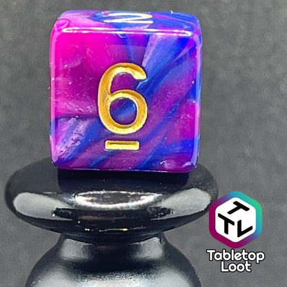 A close up of the D6 from the Spelljammin' 7 piece dice set from Tabletop Loot with pearlescent swirls of purple and blue and gold numbering.