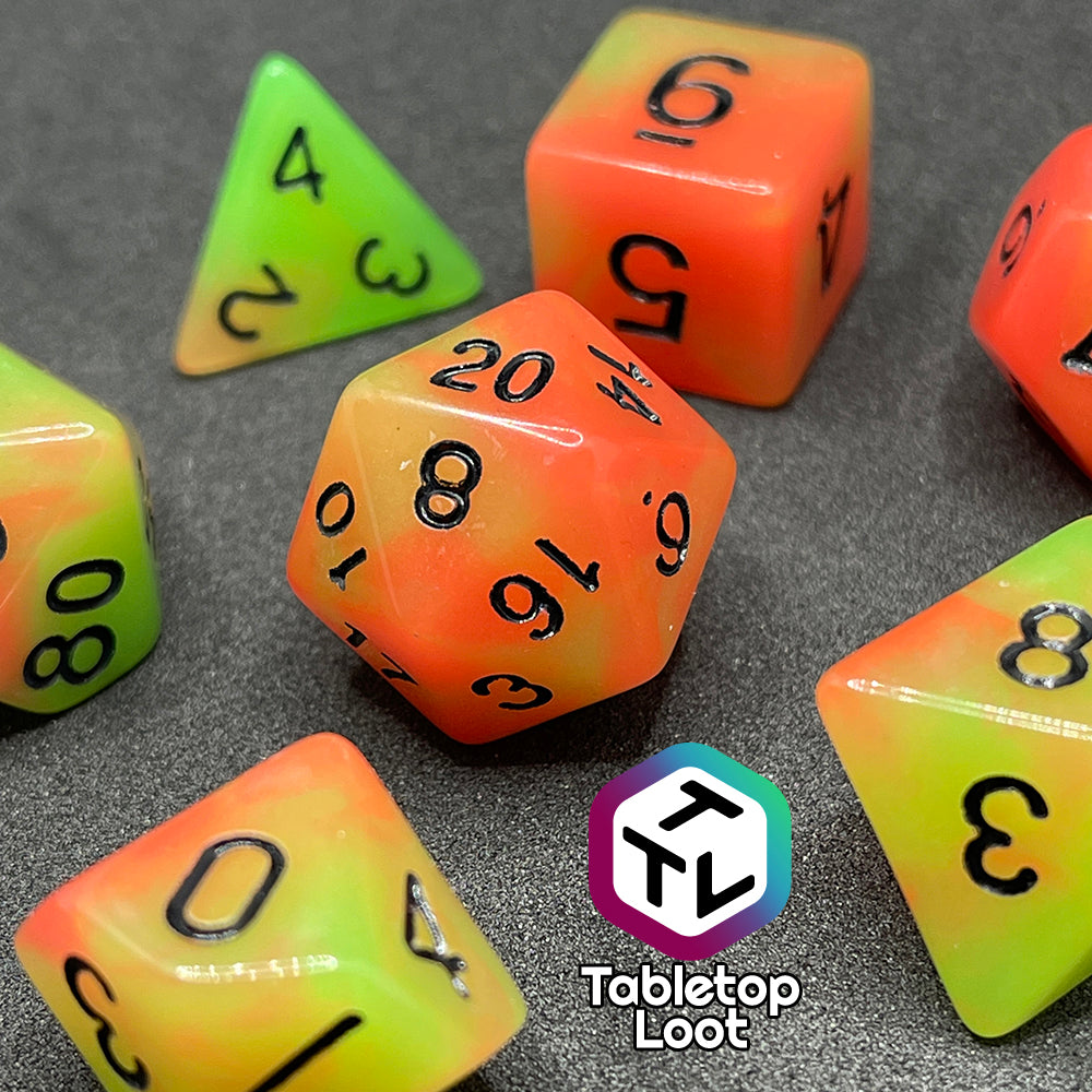 The Neon Nights glow in the dark 7 piece dice set from Tabletop Loot with swirled orange and yellow glow pigment and black numbering, shown in light.