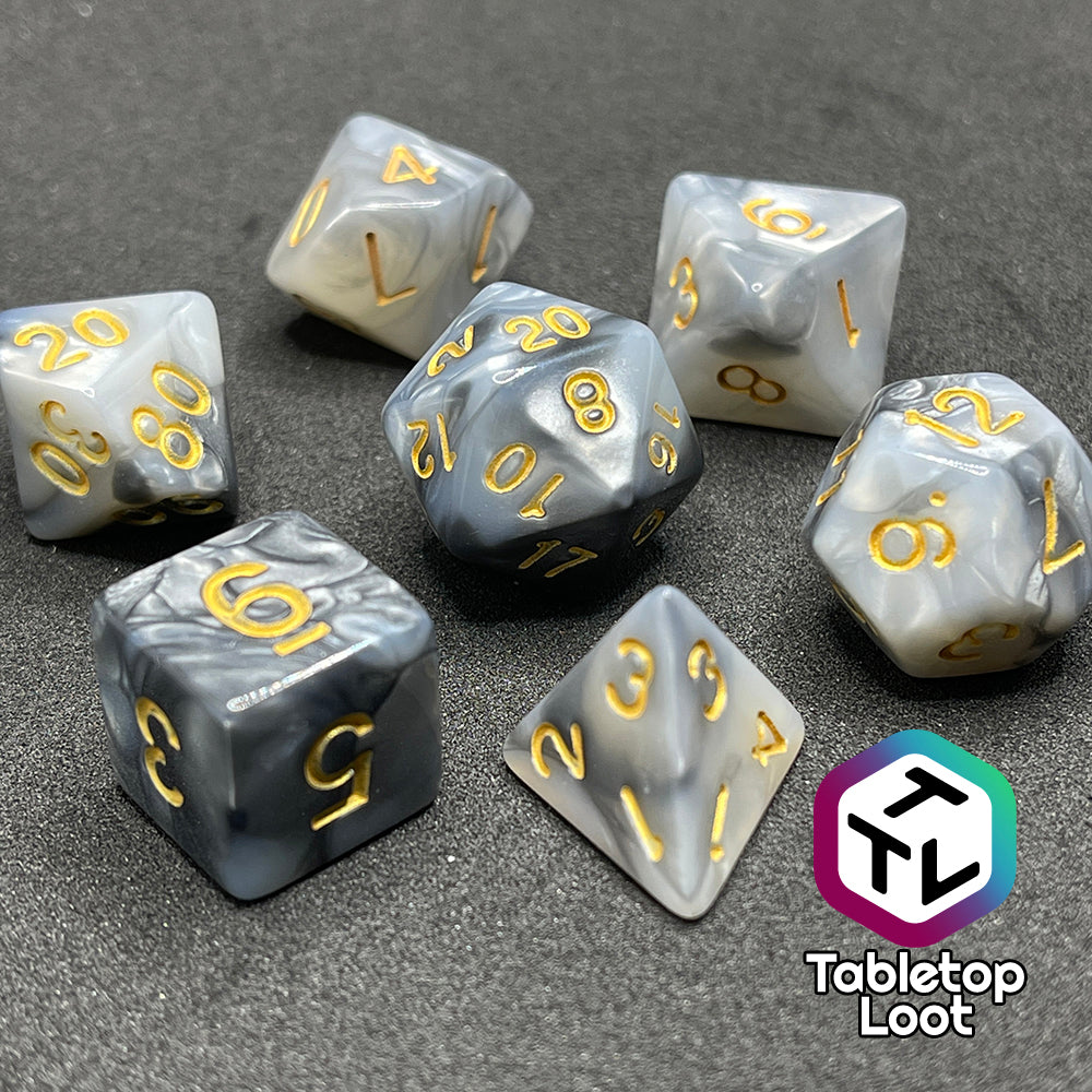 The Stone Giant 7 piece dice set with swirls of iridescent silver and white and gold numbering.