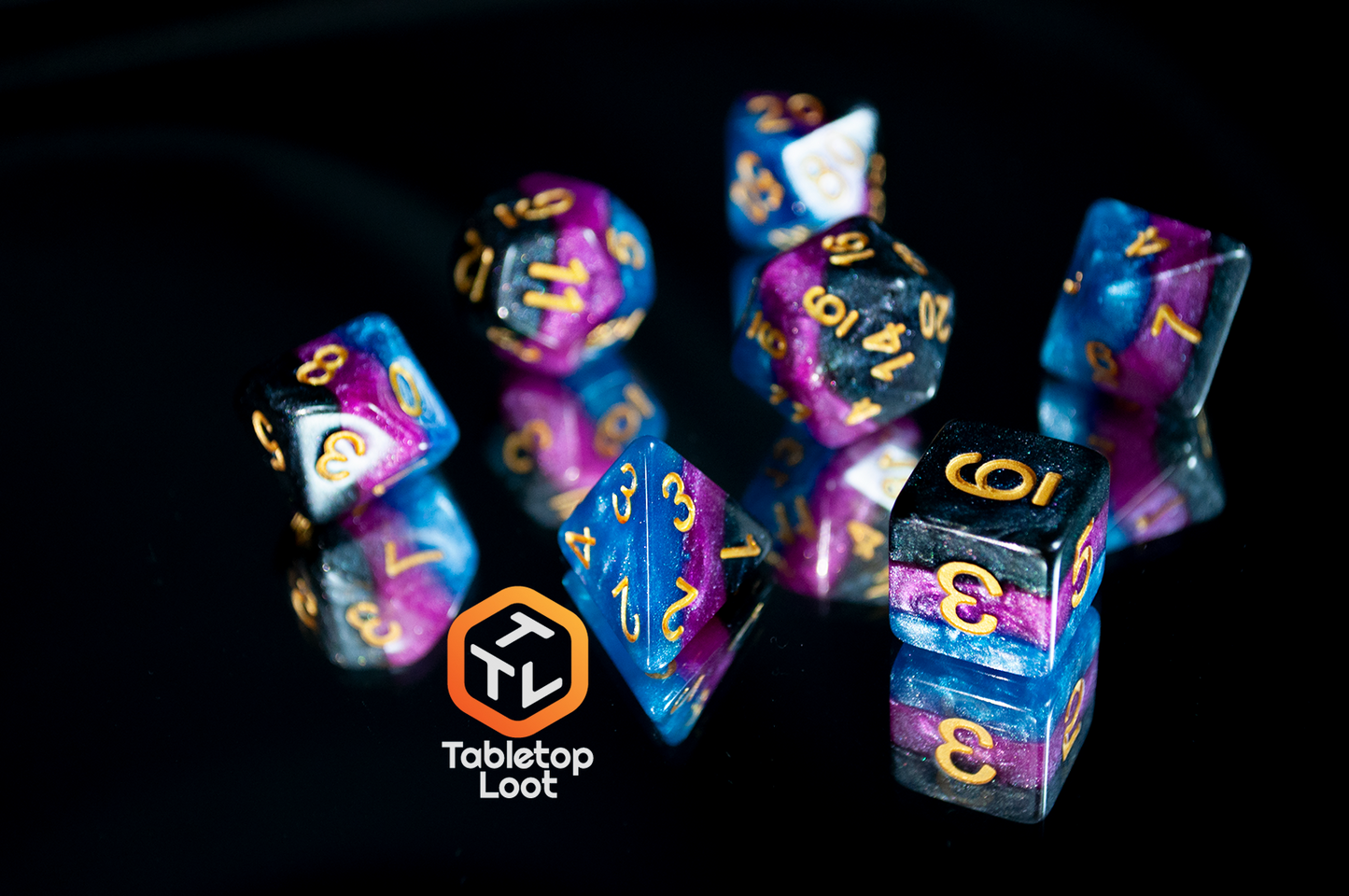 The 7 piece Pulse Wave dice set from Tabletop Loot; striped blue, purple, and black glittery dice with gold numbering.