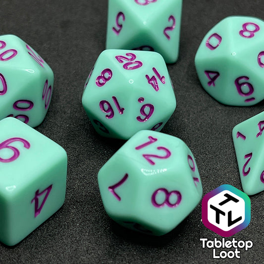 A close up of the Winterberry 7 piece dice set from Tabletop Loot with purple numbering on solid mint green dice.