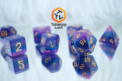 A close up of the Lavender Galaxy 7 piece dice set from Tabletop Loot with layers of pink, purple, and blue, lots of glitter, and gold numbering.
