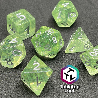 A close up of the Acid Splash 7 piece dice set from Tabletop Loot; glittery lime green translucent dice with silver numbering.