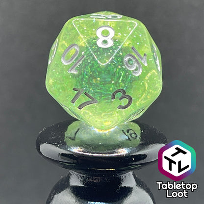 A close up of the D20 from the Acid Splash 7 piece dice set from Tabletop Loot; glittery lime green translucent dice with silver numbering.