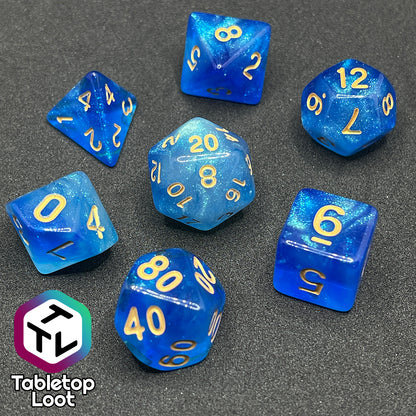 The Air Genasi 7 piece dice set from Tabletop Loot with swirls of glittering tones of blue and gold numbers.