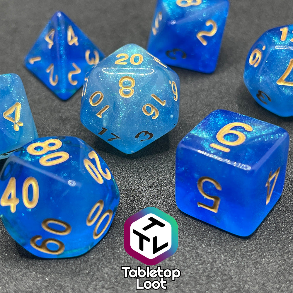 A close up of the Air Genasi 7 piece dice set from Tabletop Loot with swirls of glittering tones of blue and gold numbers.