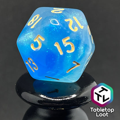 A close up of the D20 from the Air Genasi 7 piece dice set from Tabletop Loot with swirls of glittering tones of blue and gold numbers.