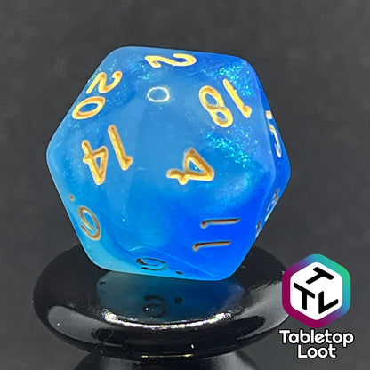 A close up of the D20 from the Air Genasi 7 piece dice set from Tabletop Loot with swirls of glittering tones of blue and gold numbers.