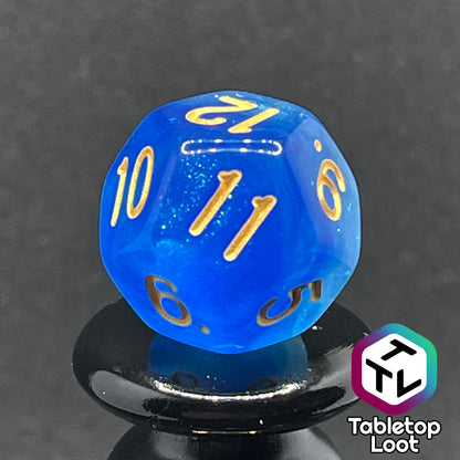 A close up of the D12 from the Air Genasi 7 piece dice set from Tabletop Loot with swirls of glittering tones of blue and gold numbers.