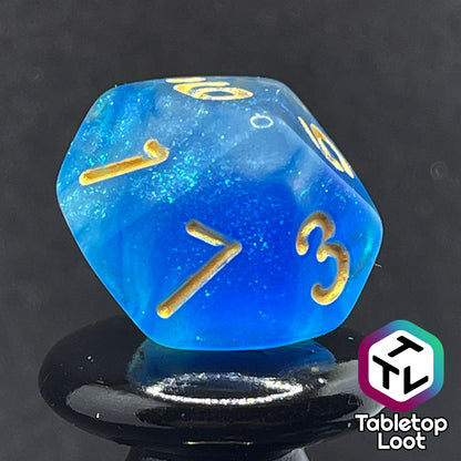 A close up of the D10 from the Air Genasi 7 piece dice set from Tabletop Loot with swirls of glittering tones of blue and gold numbers.