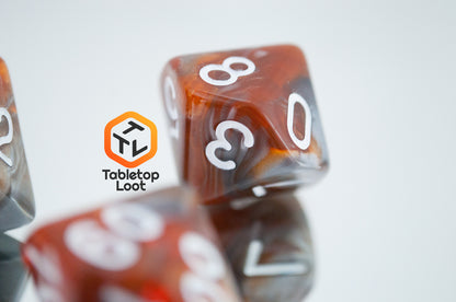 A close up of the D10 from the Amber Shard 7 piece dice set from Tabletop Loot with swirls of orange and silver resin and white numbers.