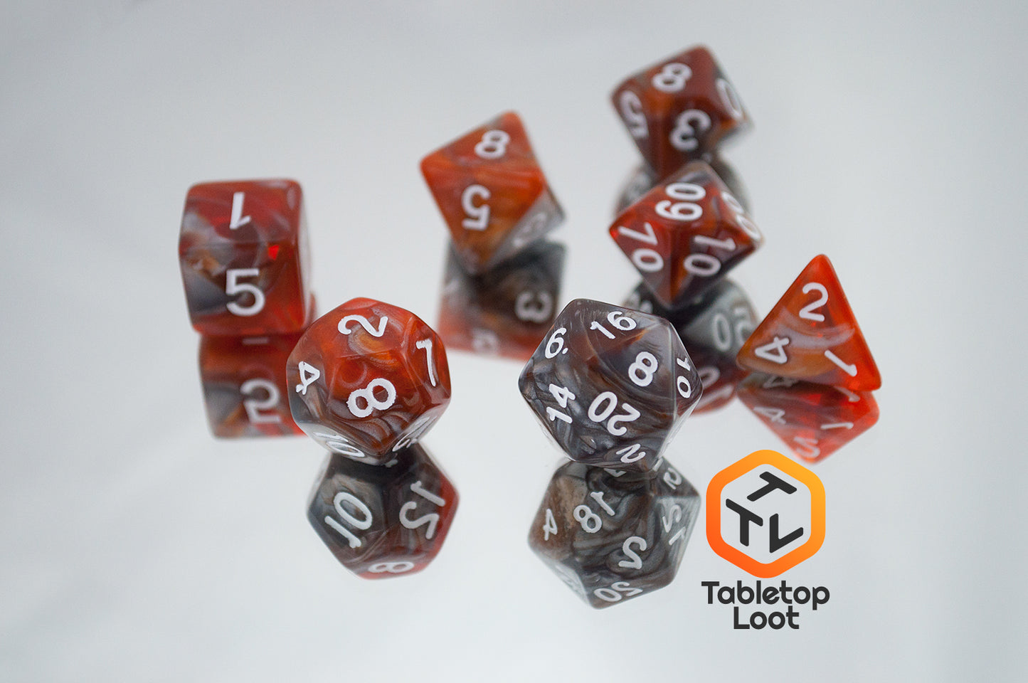 The Amber Shard 7 piece dice set from Tabletop Loot with swirls of orange and silver resin and white numbers.