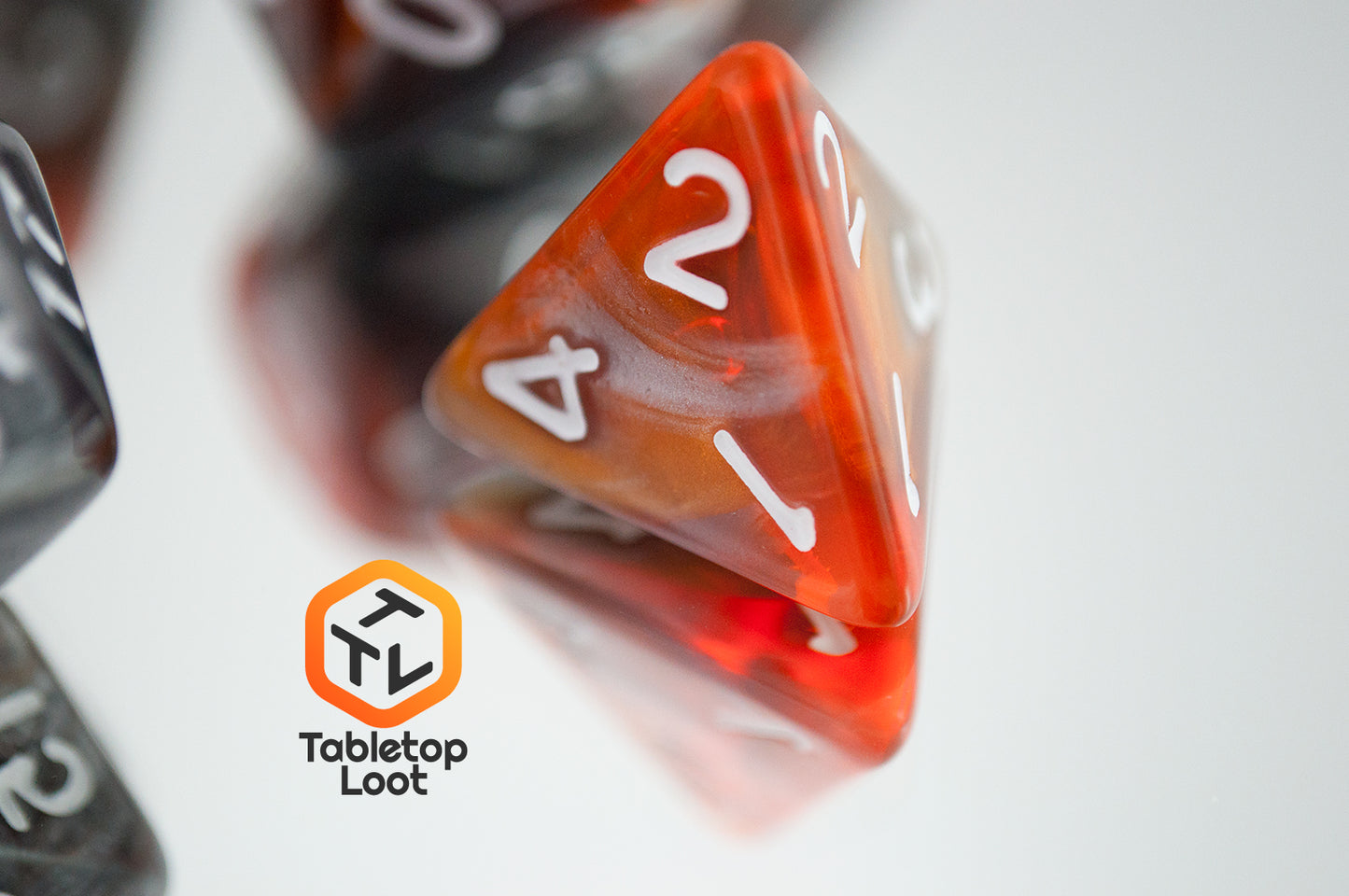 A close up of the D4 from the Amber Shard 7 piece dice set from Tabletop Loot with swirls of orange and silver resin and white numbers.