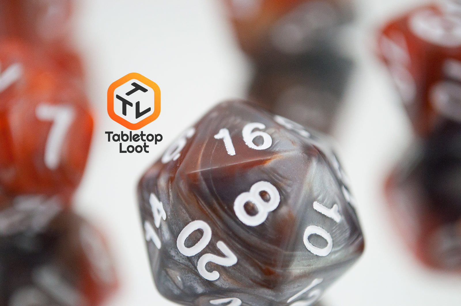 A close up of the D20 from the Amber Shard 7 piece dice set from Tabletop Loot with swirls of orange and silver resin and white numbers.