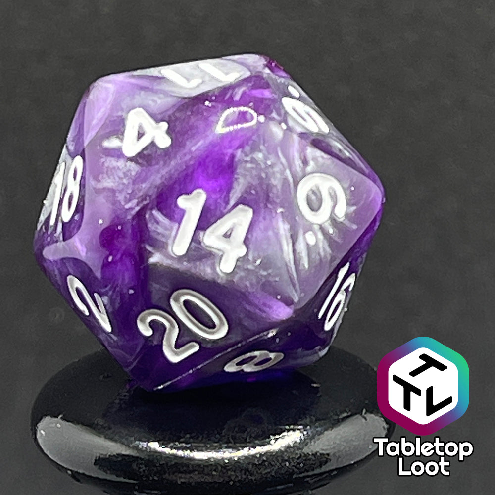 A close up of the D20 from the Amethyst Dreams 7 piece dice set with swirls of purple and silver and white numbering.