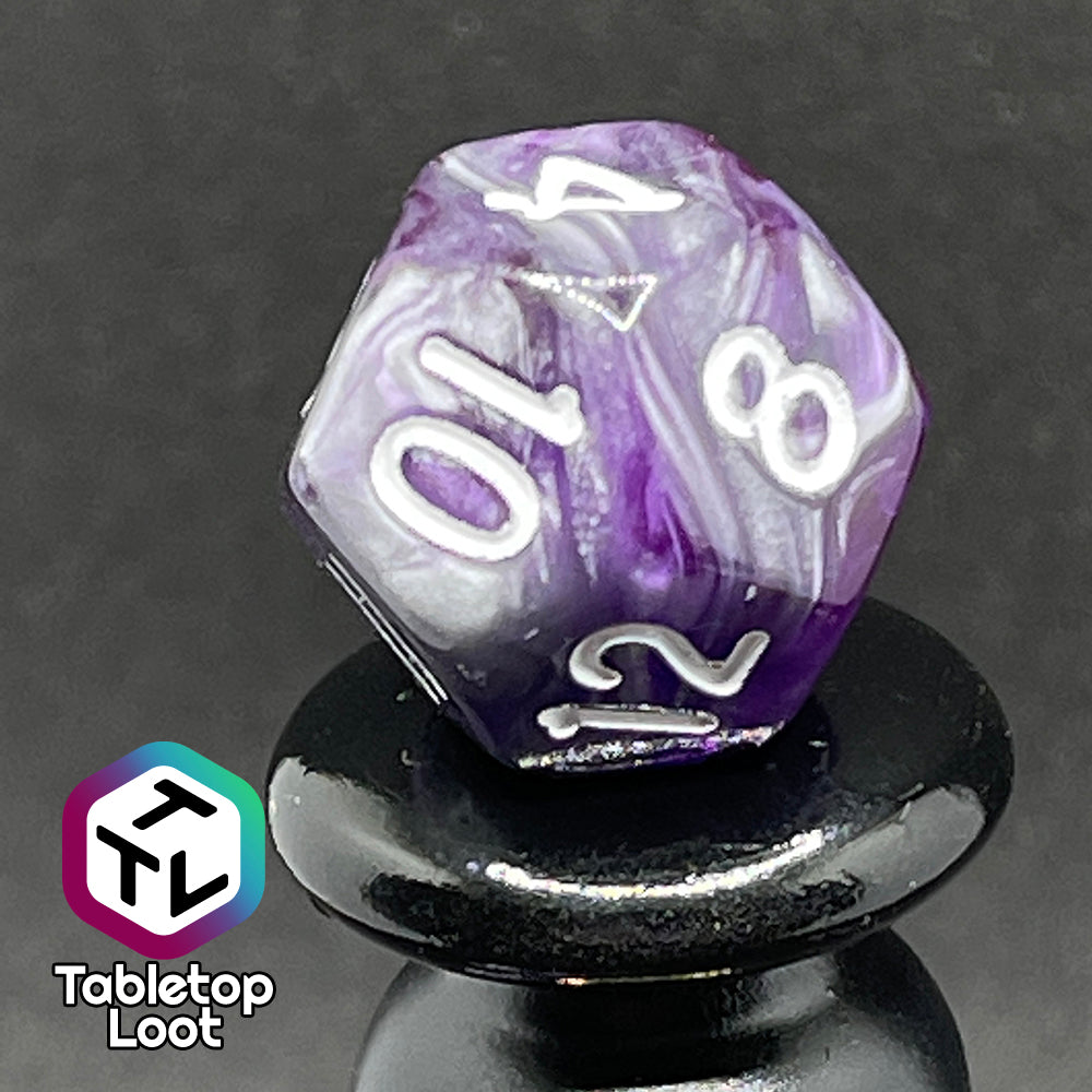 A close up of the D12 from the Amethyst Dreams 7 piece dice set with swirls of purple and silver and white numbering.