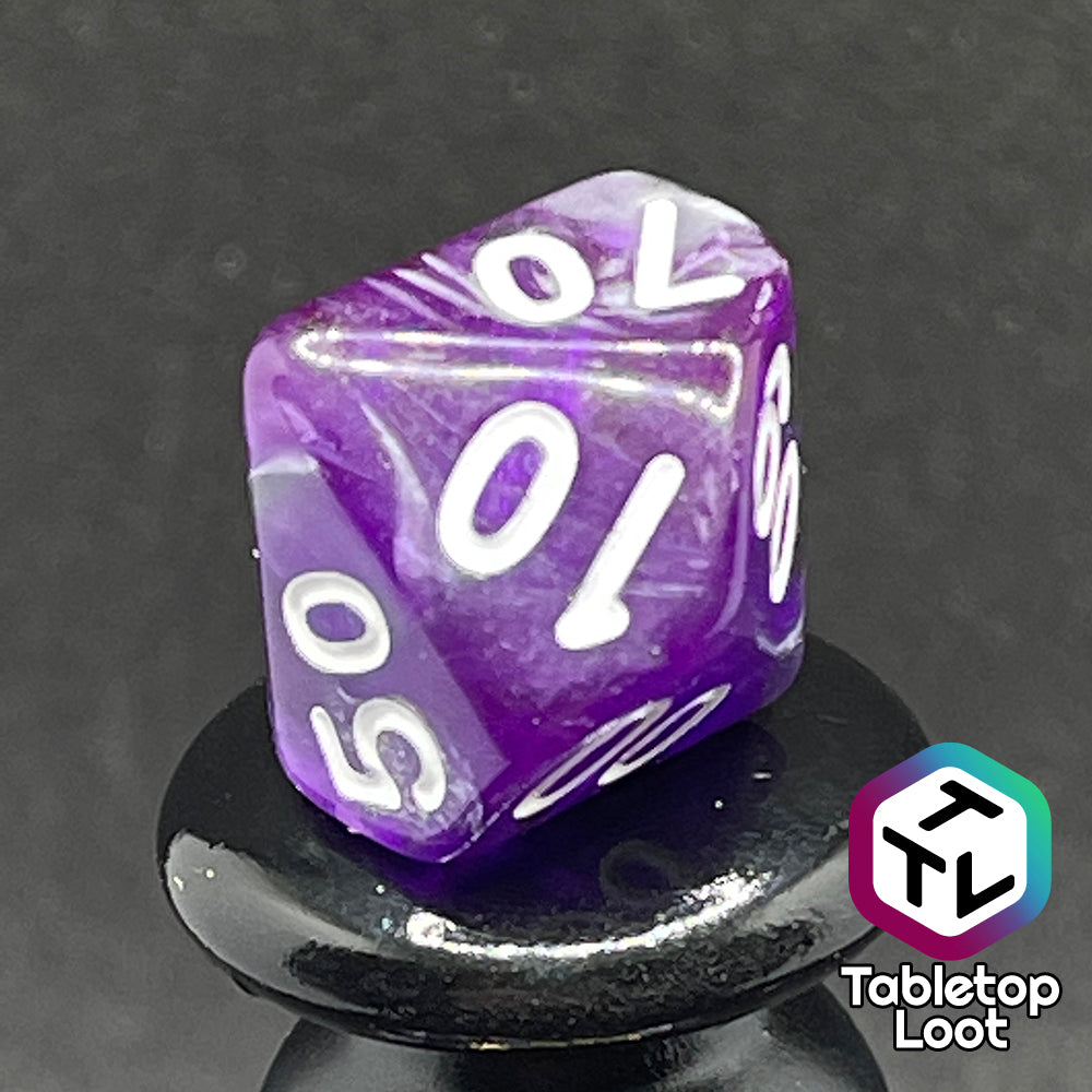 A close up of the percentile dire from the Amethyst Dreams 7 piece dice set with swirls of purple and silver and white numbering.