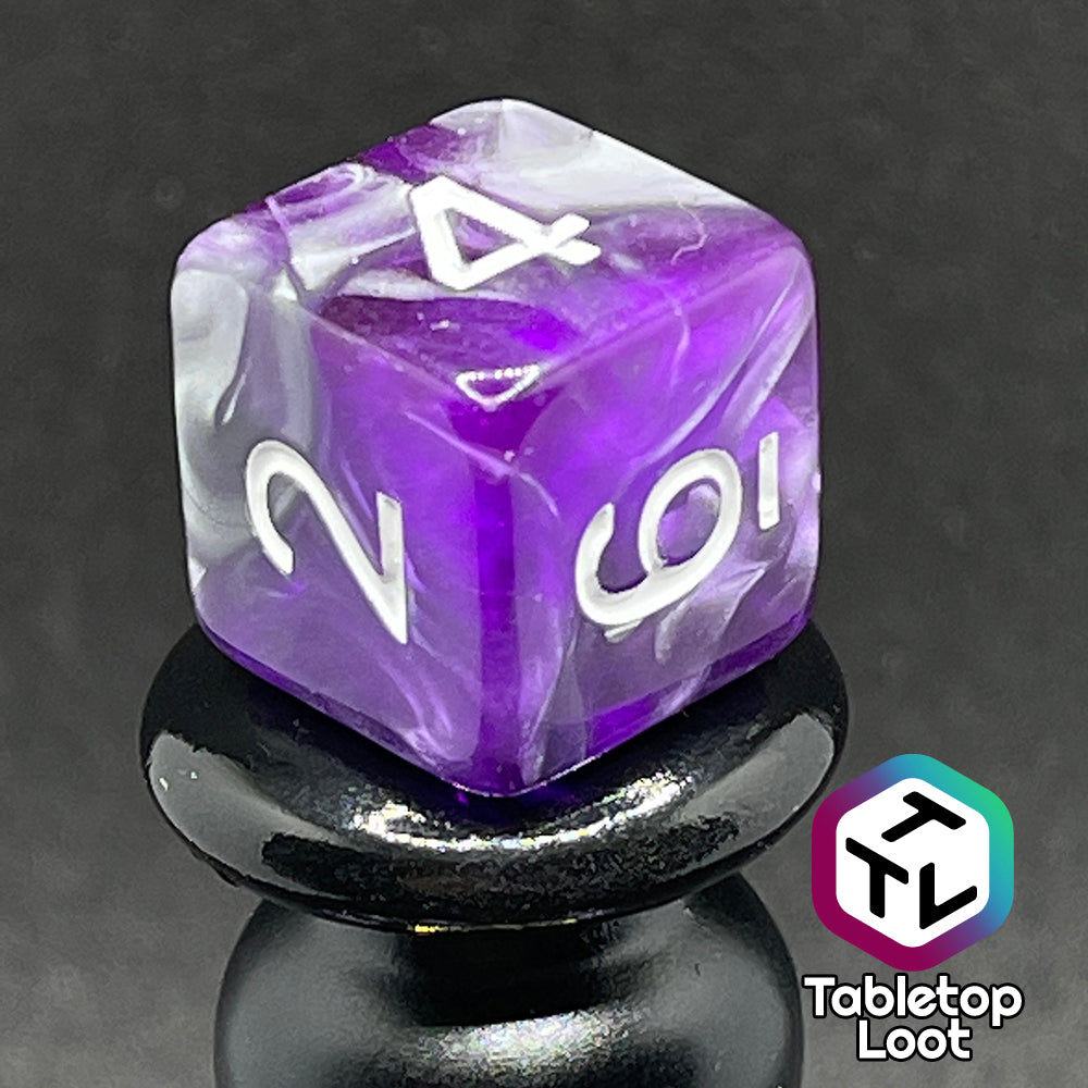 A close up of the D6 from the Amethyst Dreams 7 piece dice set with swirls of purple and silver and white numbering.