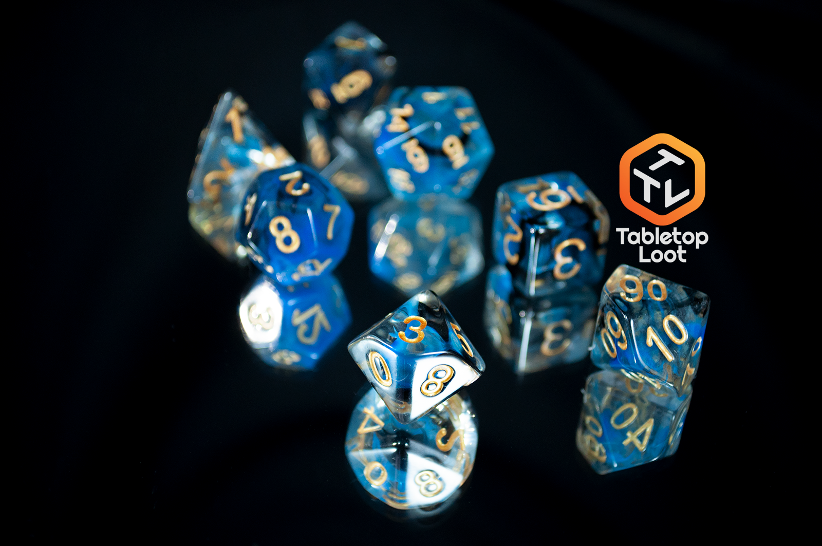 The Arcane Eye 7 piece dice set from Tabletop Loot with swirls of blue and black in clear dice and gold numbering.