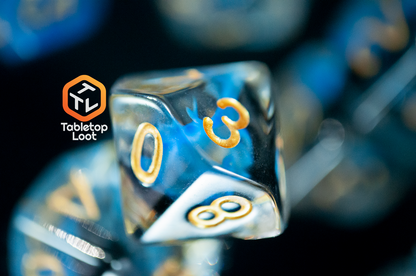 A close up of the D10 from the Arcane Eye 7 piece dice set from Tabletop Loot with swirls of blue and black in clear dice and gold numbering.