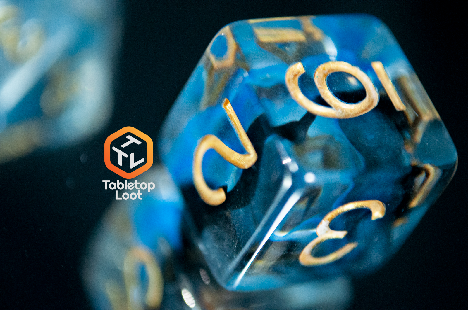 A close up of the D6 from the Arcane Eye 7 piece dice set from Tabletop Loot with swirls of blue and black in clear dice and gold numbering.