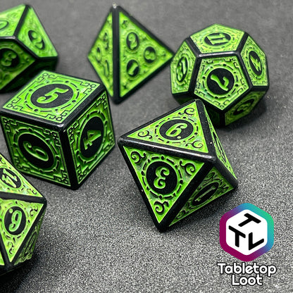 A close up of the Artificer's Delight 7 piece dice set from Tabletop Loot with bold, neon green numbers on intricate scrolling black frames that make up each side.