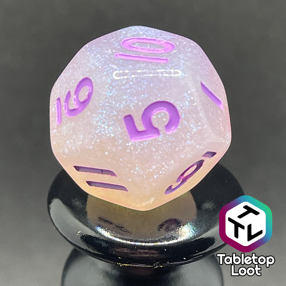 A close up of the D12 from the Astral Projection 7 piece dice set from Tabletop Loot with lavender numbering on milky dice with iridescent shimmer.