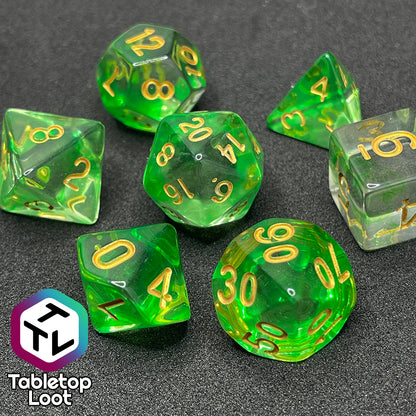 A close up of the Aura of the Traveler 7 piece dice set from Tabletop Loot with swirls of lime green in clear dice with gold numbering.