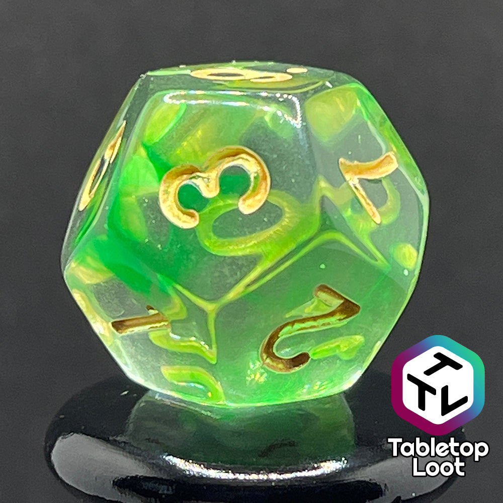 A close up of the D12 from the Aura of the Traveler 7 piece dice set from Tabletop Loot with swirls of lime green in clear dice with gold numbering.