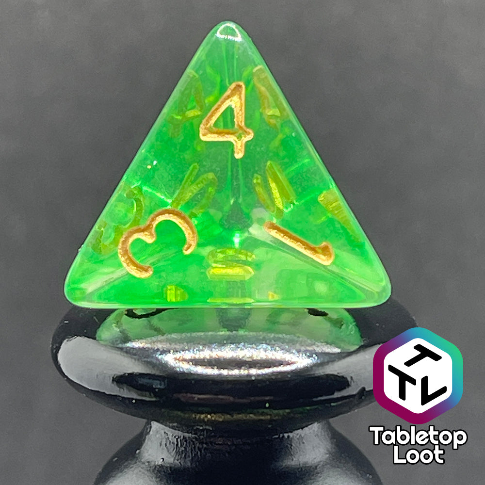 A close up of the D4 from the Aura of the Traveler 7 piece dice set from Tabletop Loot with swirls of lime green in clear dice with gold numbering.