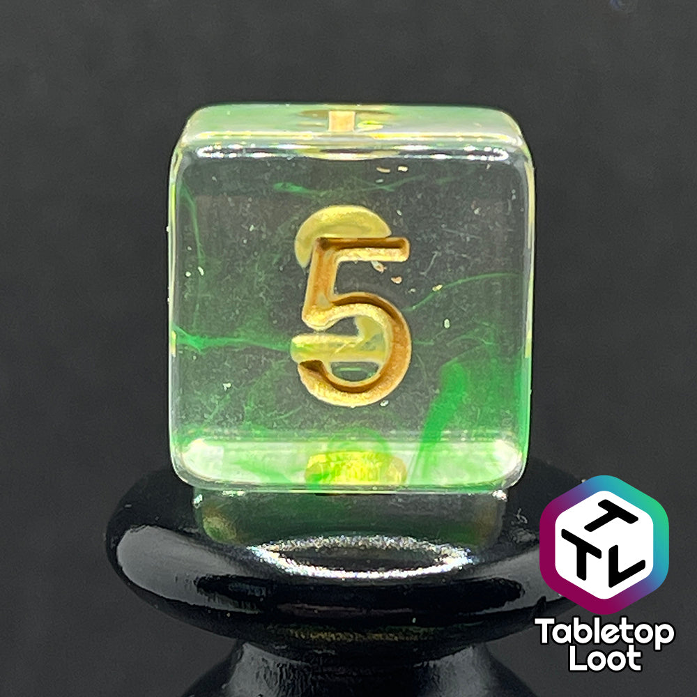 A close up of the D6 from the Aura of the Traveler 7 piece dice set from Tabletop Loot with swirls of lime green in clear dice with gold numbering.