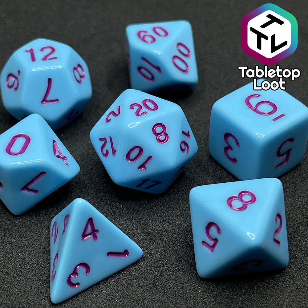 A close up of the Bantha Milk 7 piece dice set from Tabletop Loot with purple numbering on solid pastel blue faces.
