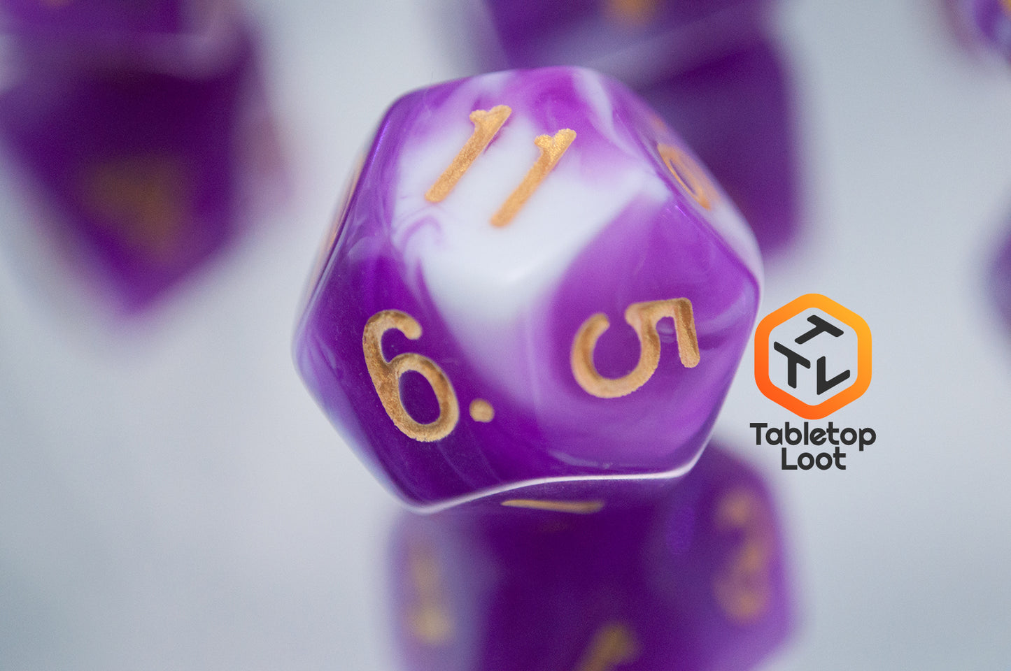 A close up of the D12 from the Berry Blast 7 piece dice set from Tabletop Loot with swirls of purple and white and gold numbering.