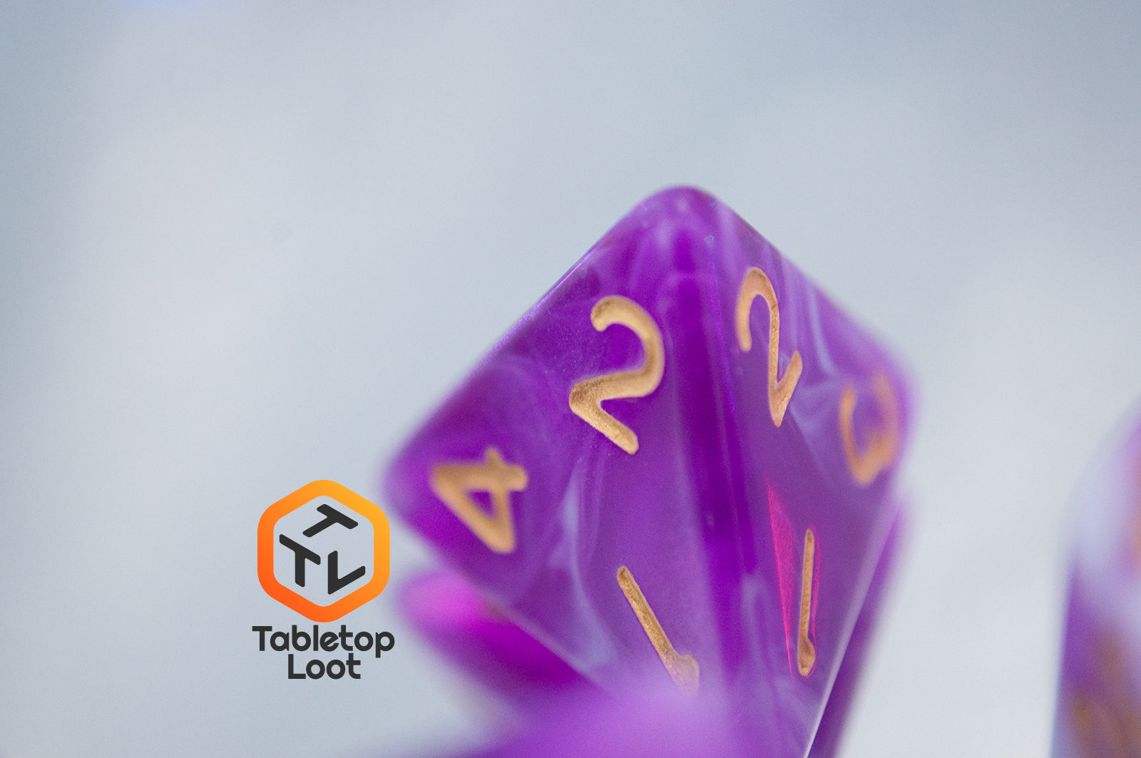 A close up of the D4 from the Berry Blast 7 piece dice set from Tabletop Loot with swirls of purple and white and gold numbering.