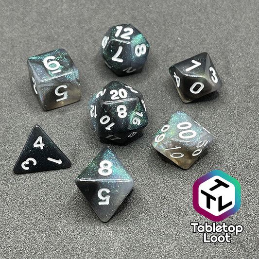 The Black Moonstone 7 piece dice set from Tabletop Loot with swirls of black and teal iridescent glitter, inked in white.