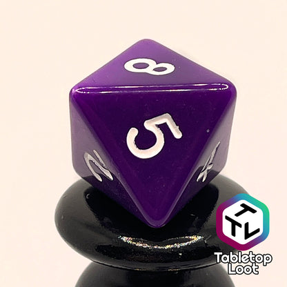 A close up of the D8 from the Blackberries 7 piece dice set; solid purple with white numbering.