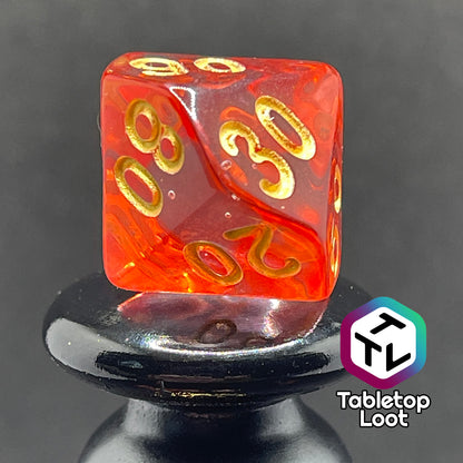 A close up of the percentile die from the Blood Hunter 7 piece dice set from Tabletop Loot with swirled red and clear resin and gold numbering.