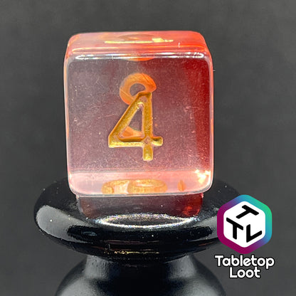 A close up of the D6 from the Blood Hunter 7 piece dice set from Tabletop Loot with swirled red and clear resin and gold numbering.
