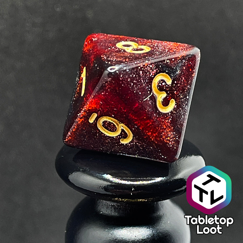 A close up of the D8 from the Blood Lust 7 piece dice set from Tabletop Loot with swirls of dark glittery red which looks almost black and gold numbering.