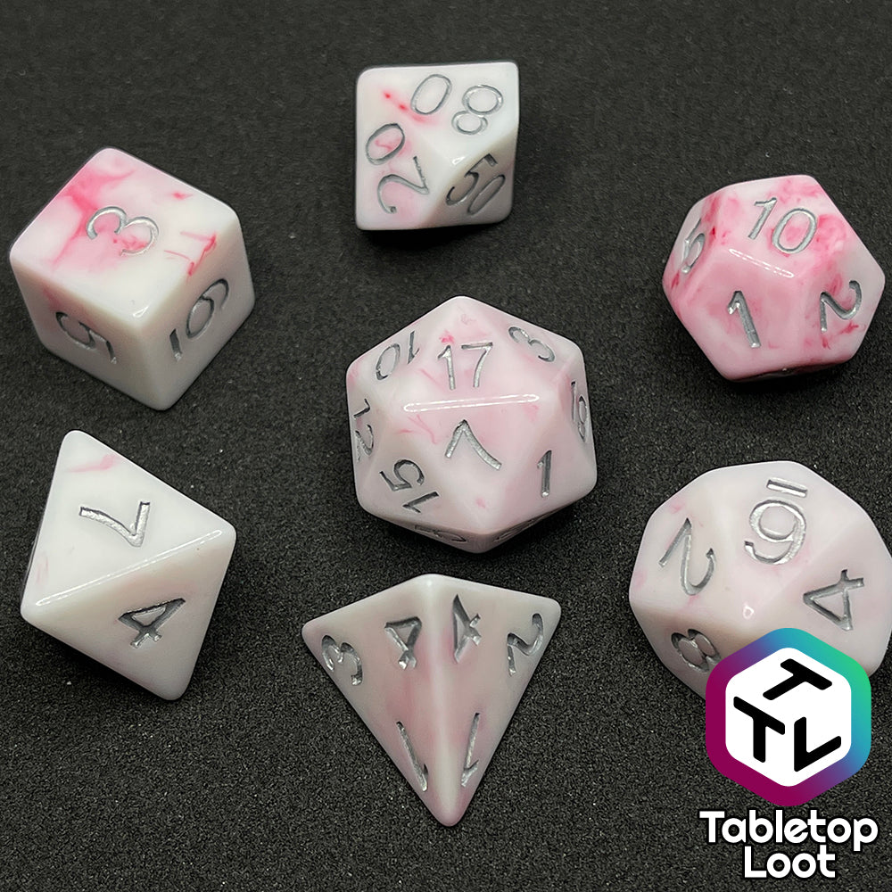 The Blood Oath 7 piece dice set from Tabletop Loot; opaque white with swirls of red peeking out and silver numbers.