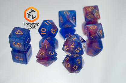 The Blue Enchantress 7 piece dice set from Tabletop Loot with shimmering shades of pink, purple, and blue swirling resin and gold numbering.